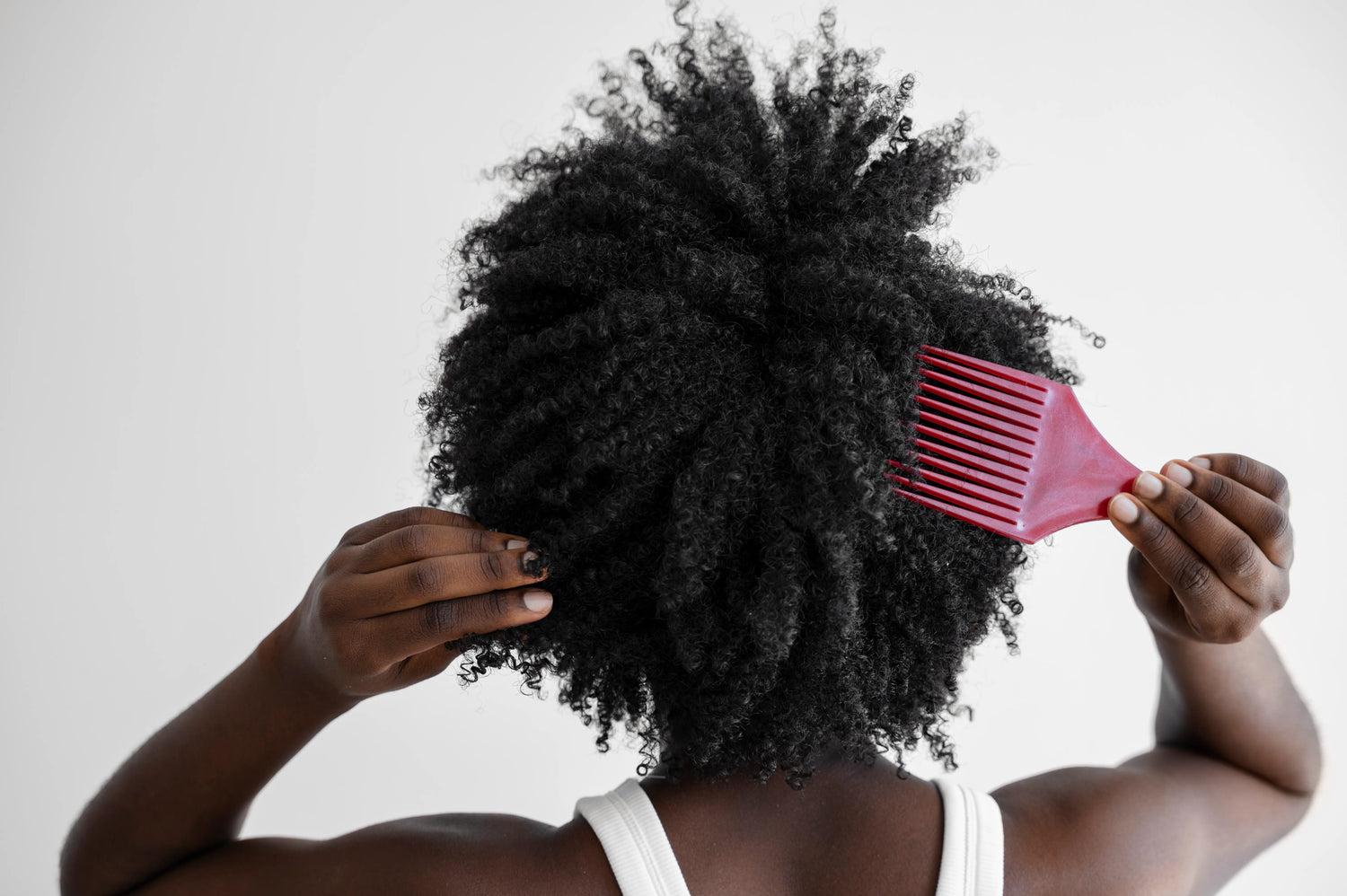 Femme aux cheveux afro naturels utilisant une brosse pour entretenir et définir ses boucles afro