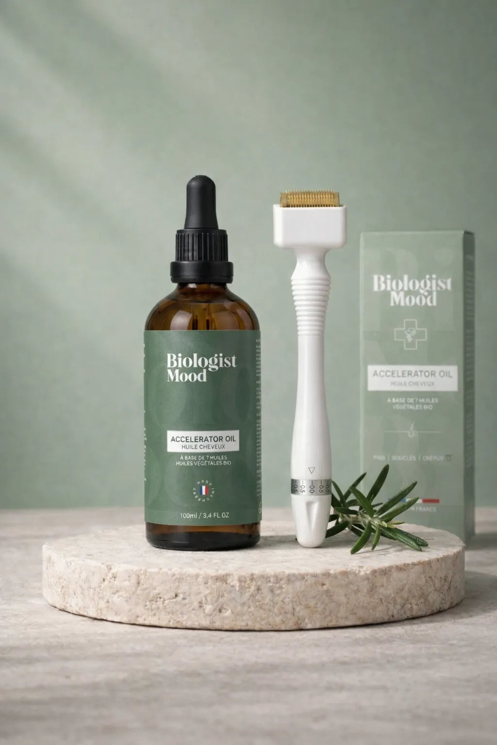 Dermastamp microneedling tool with natural hair growth oil bottle on a stone surface, used as a scalp treatment to stimulate hair regrowth and reduce hair thinning