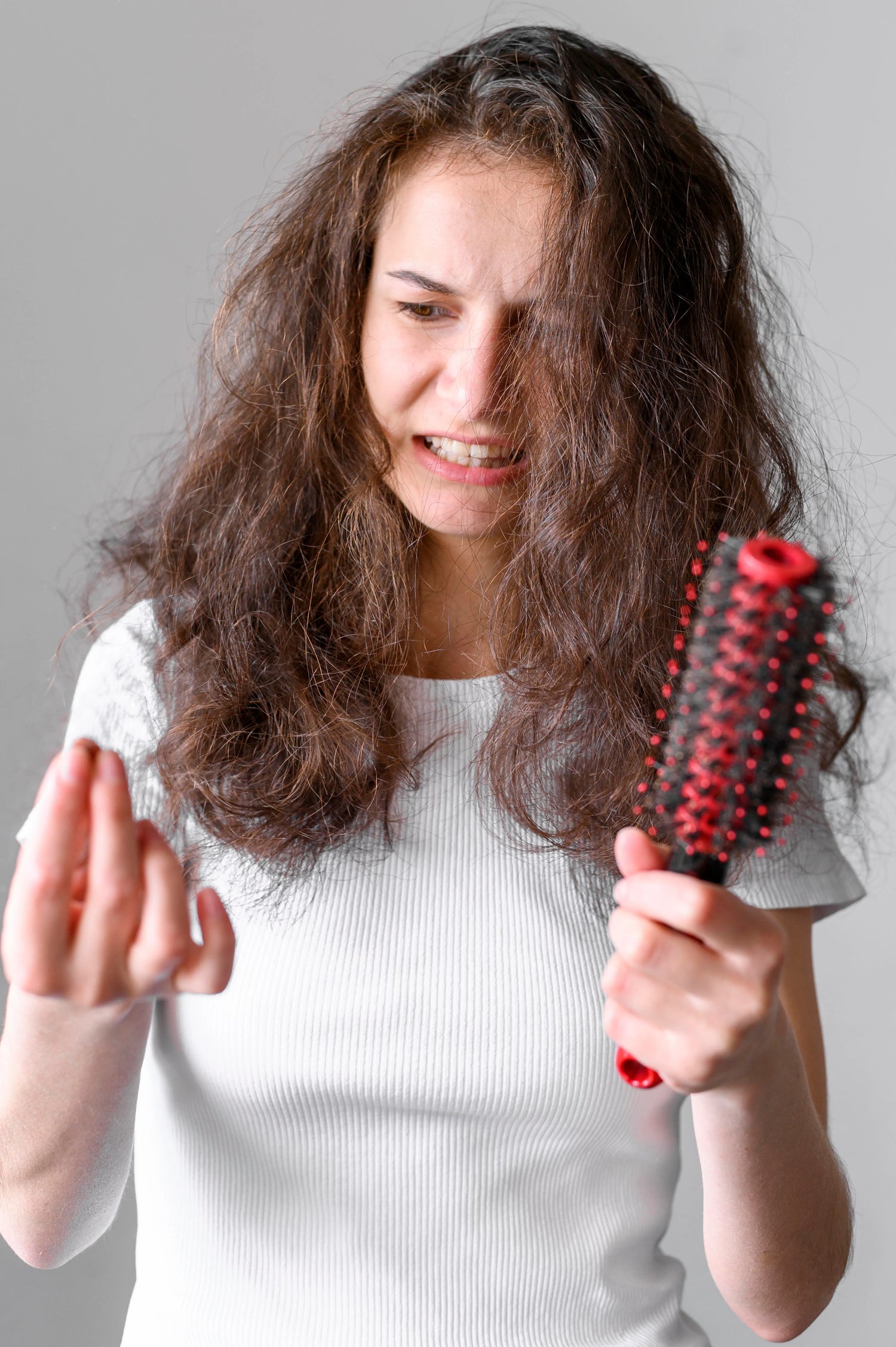 Femme avec les cheveux emmêlés inquiète en tenant une brosse remplie de cheveux
