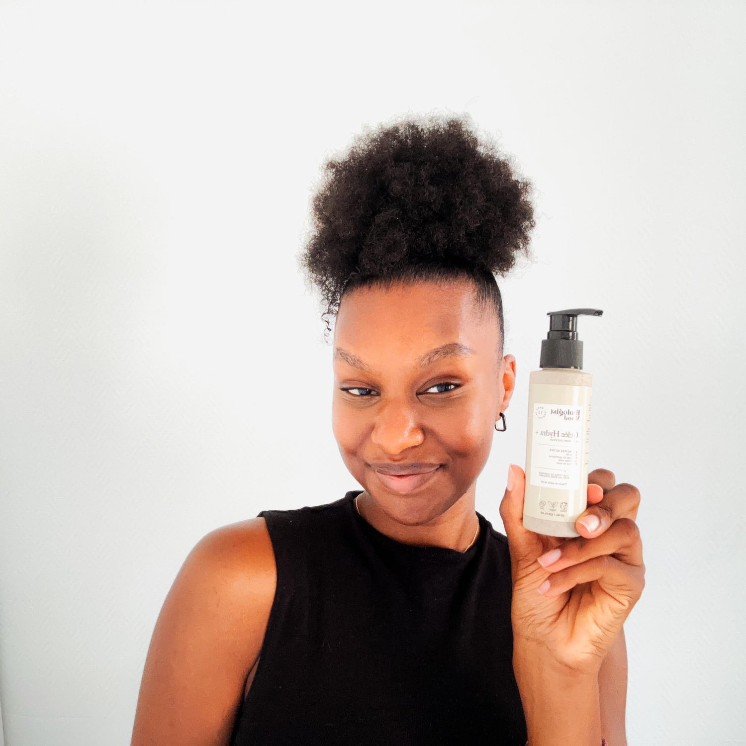 Femme aux cheveux crépus tenant un soin capillaire pour hydrater et nourrir les cheveux frisés secs