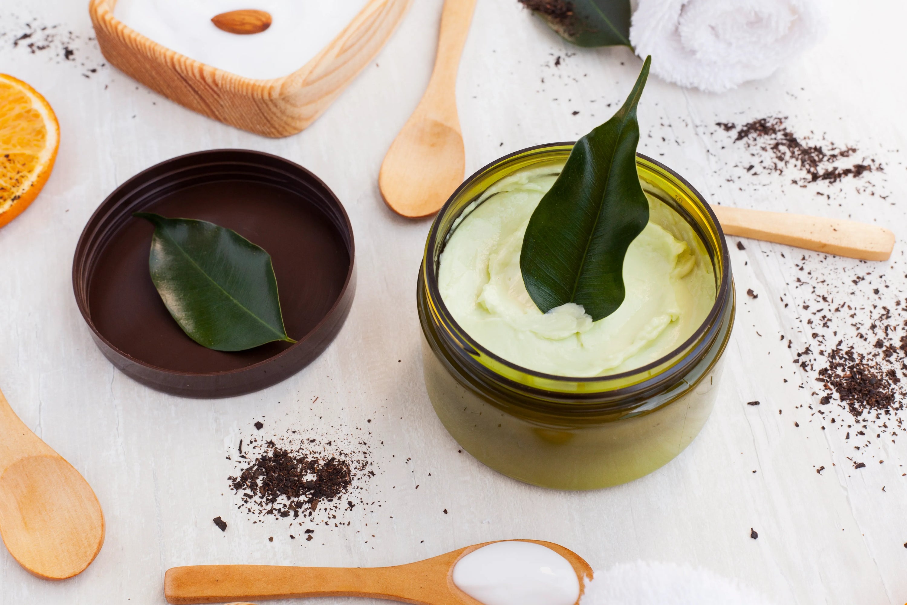 Produits de soin capillaire naturels disposés sur une table en bois pour illustrer un gommage du cuir chevelu et une routine anti-pellicules.