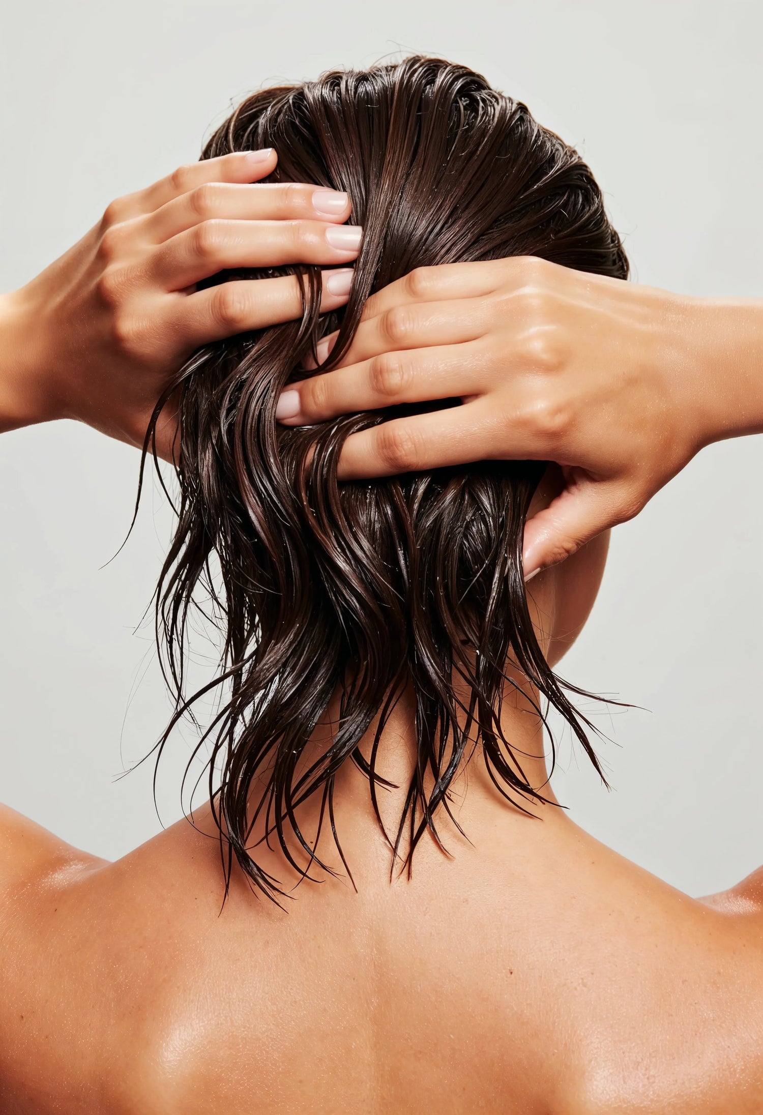 Femme appliquant un gommage sur son cuir chevelu humide sous la douche, exfoliation capillaire naturelle