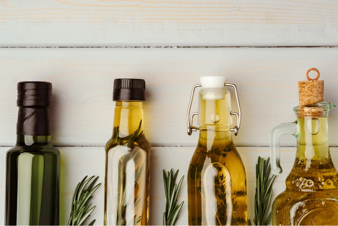 Bouteilles en verre remplies d’huiles naturelles, riches en romarin, ricin et fenugrec, utilisées pour stimuler la pousse des cheveux de manière naturelle.