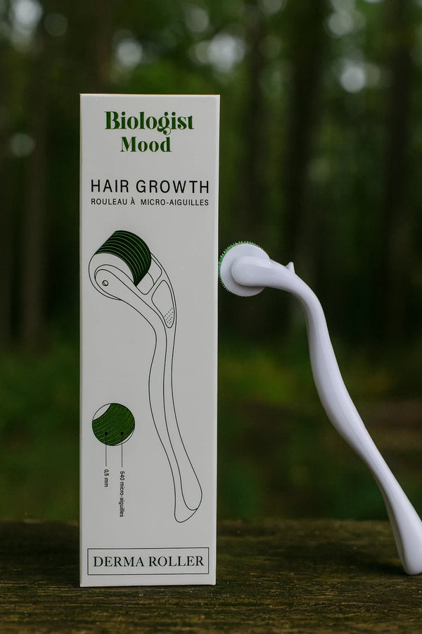  Dermaroller Biologist Mood pour la pousse des cheveux, présenté sur une surface naturelle en bois avec un fond vert, symbole de repousse capillaire naturelle.