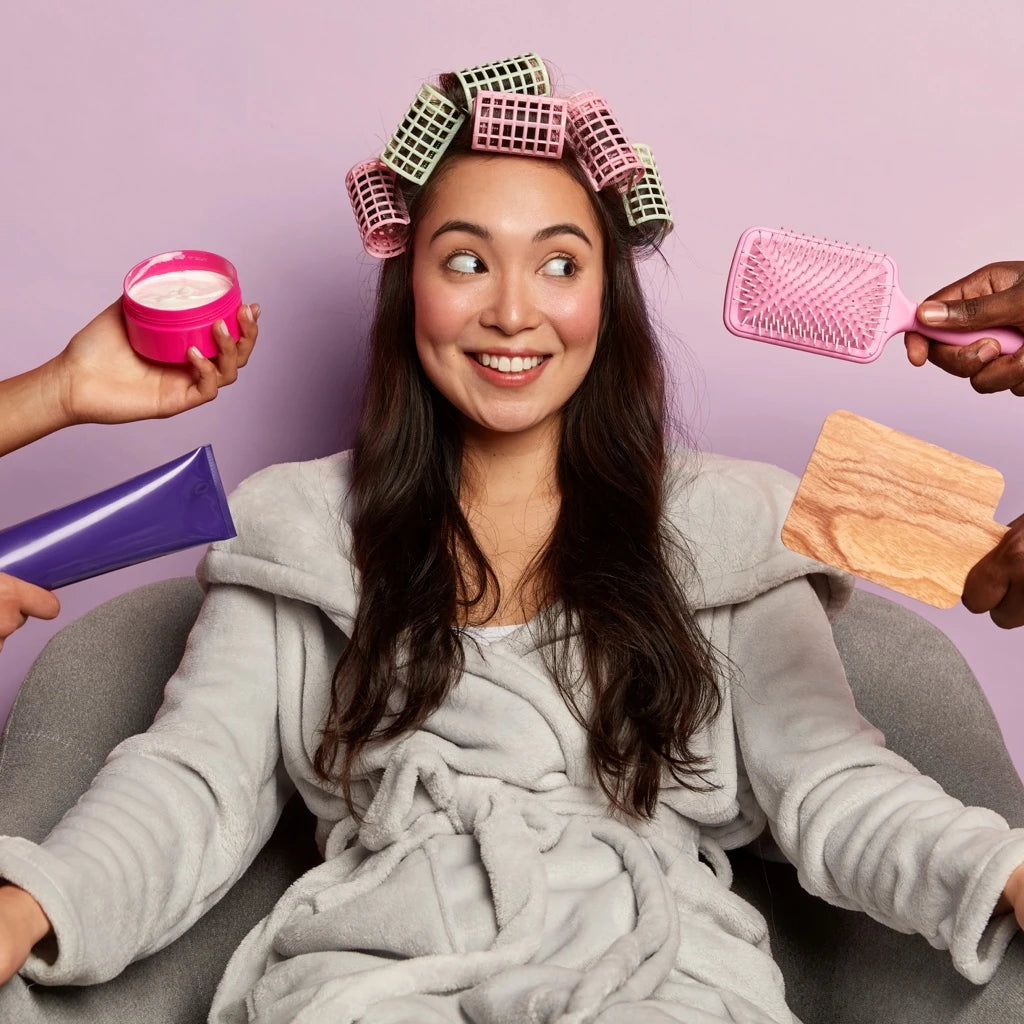 femme souriante en peignoir recevant un soin capillaire à domicile avec brosses et produits naturels — routine beauté pour cheveux sains et brillants.